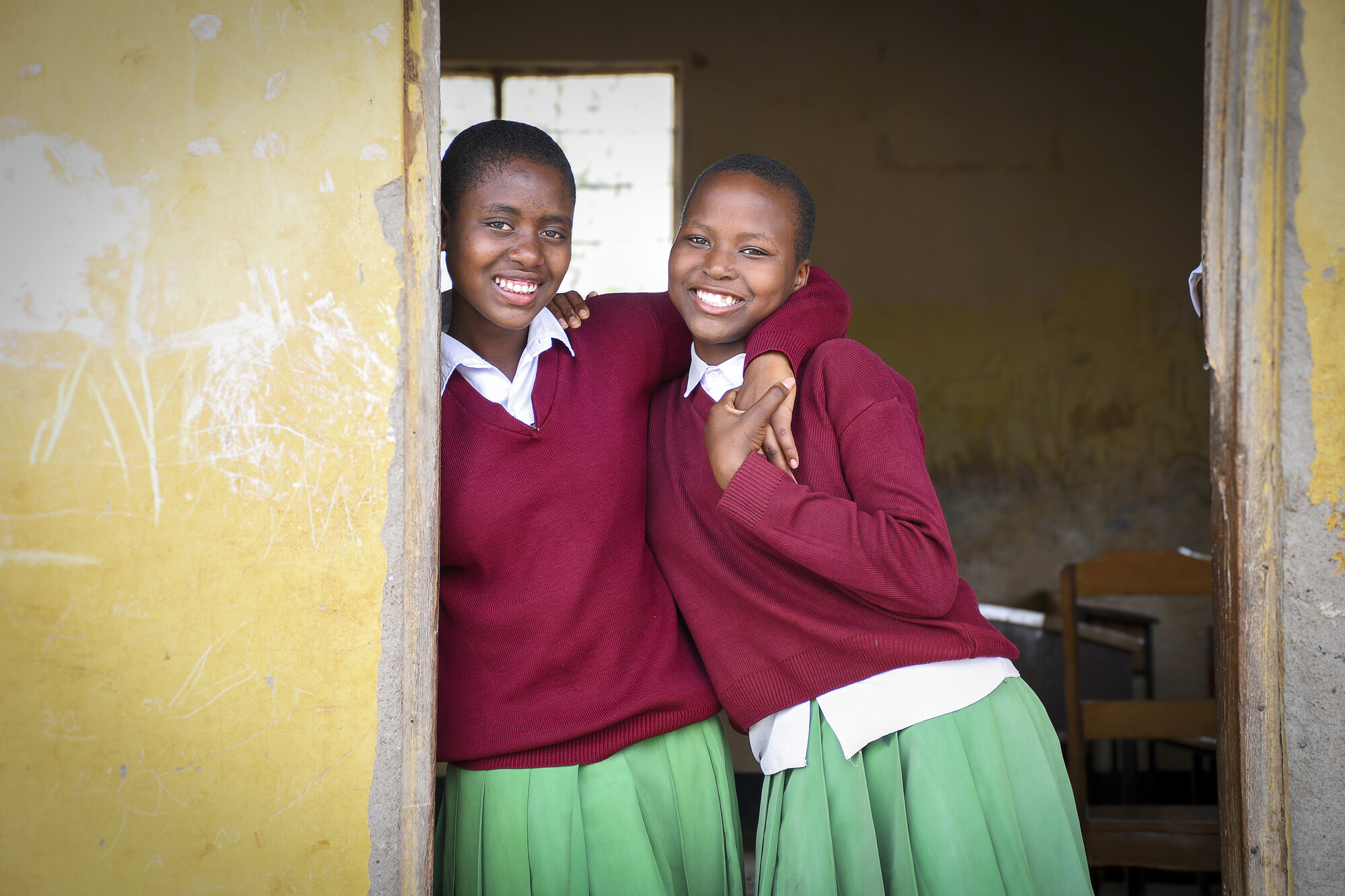 Diana y su amiga fuera de la escuela en Tanzania, se abrazan