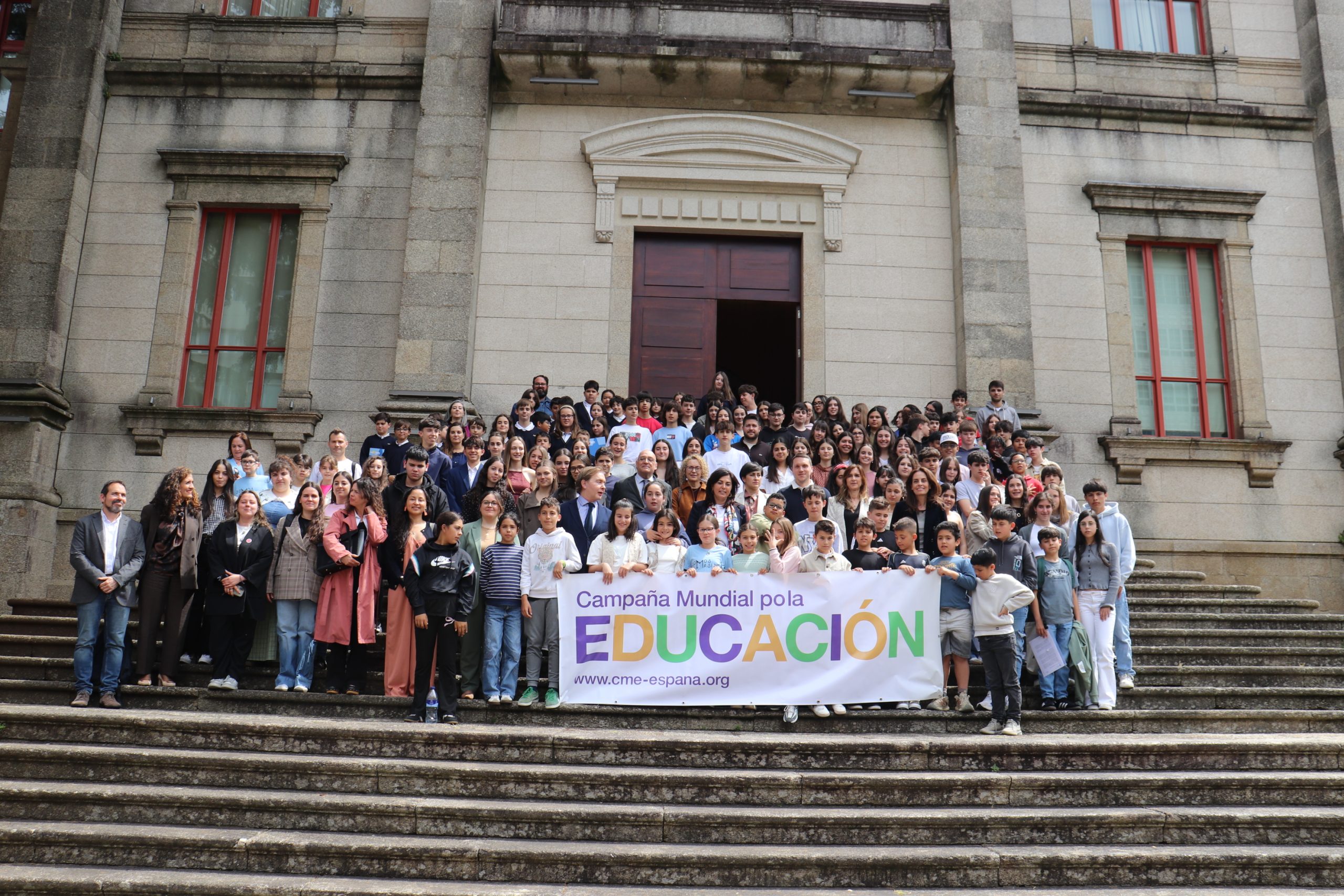 Estudiantes en una escalera posando con un cartel de la Campaña Mundial por al educación